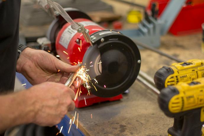 person in front of red bench grinder